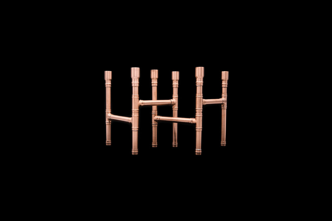 Two copper candle holders shown interlocked together on a solid black background.