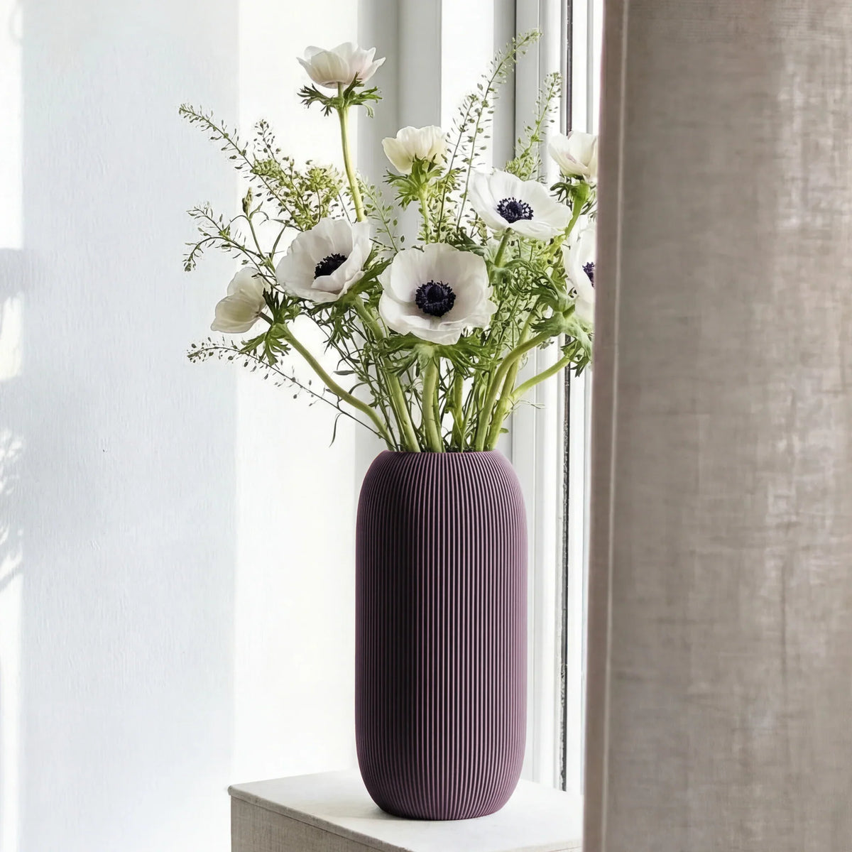 Dusky-purple vase with white flowers on a windowsill