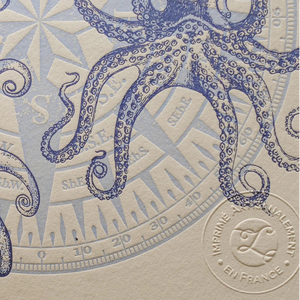 A close up of vintage-style illustrated art print with illustrations of an octopus and compass in the background on off-white cotton paper, showing the embossed stamp of authenticity.