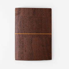 Brown cork notebook with a orange elastic band on a white background