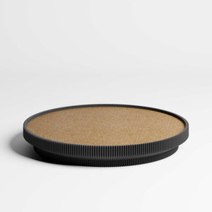 A round tray with a cork top and a black ribbed rim, photographed on a clean white studio background.