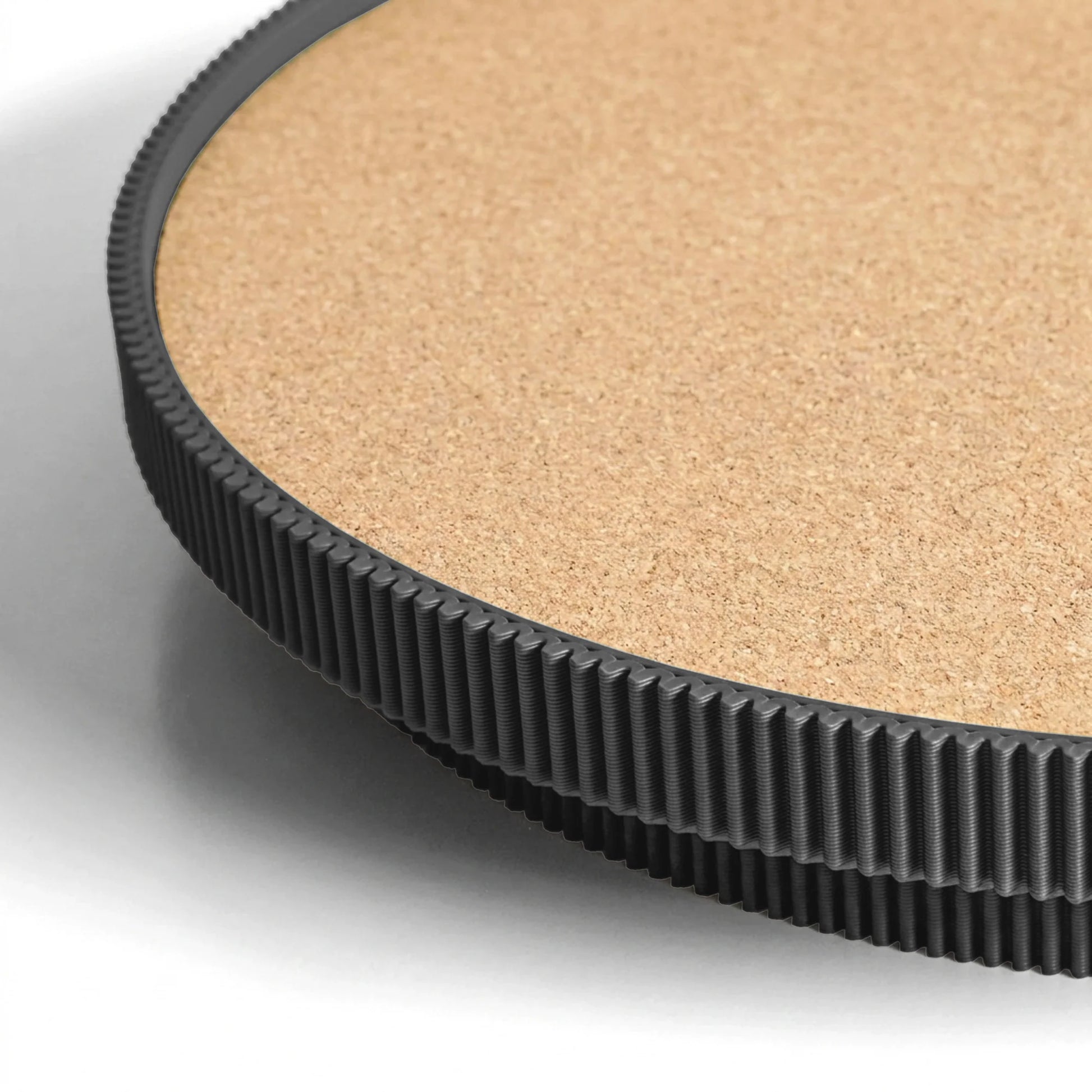 Close-up of a black circular serving tray with a cork top on a light gray background