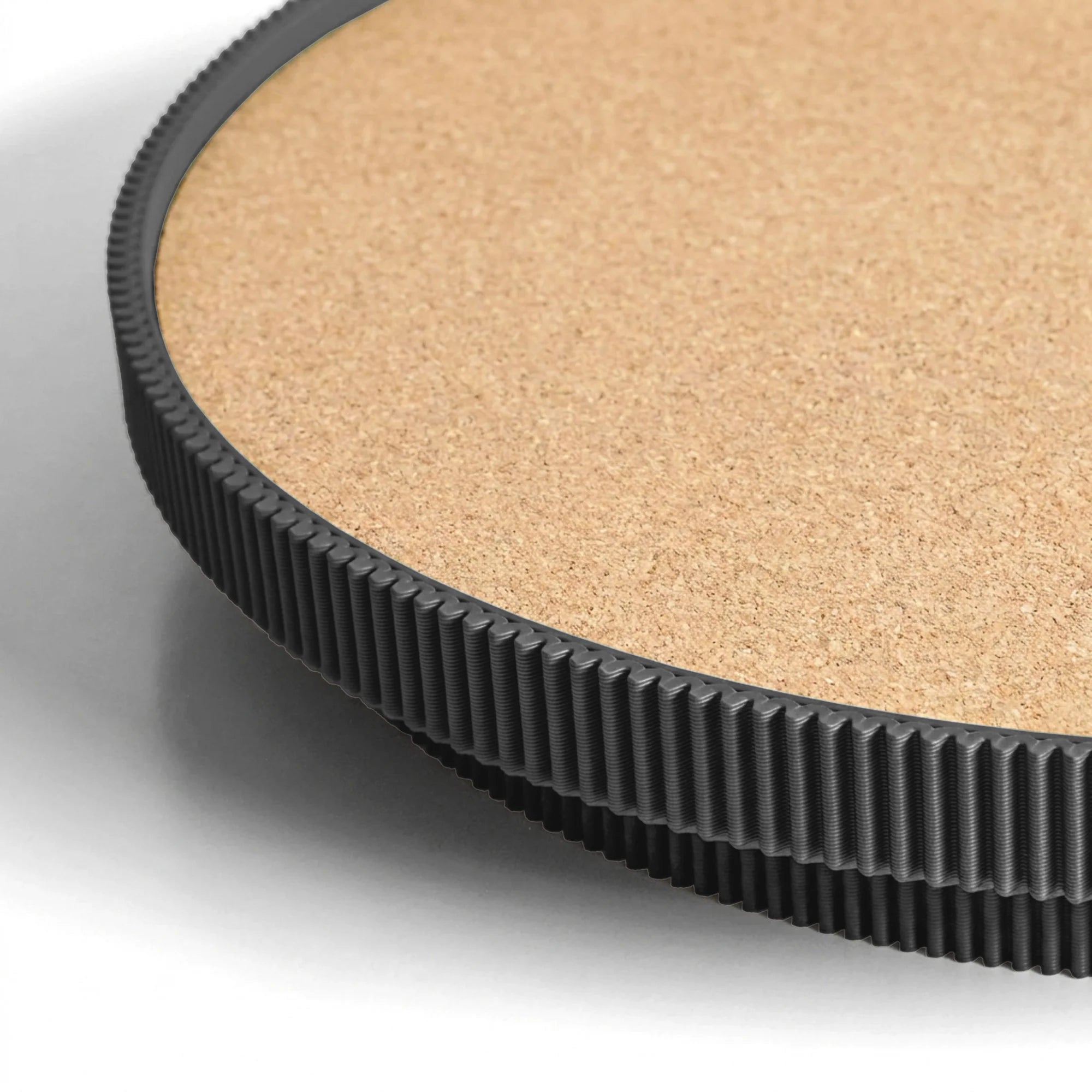 Close-up of a black circular serving tray with a cork top on a light gray background