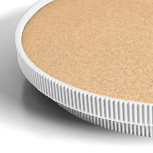 Close-up of a white circular serving tray with a cork top on a light gray background