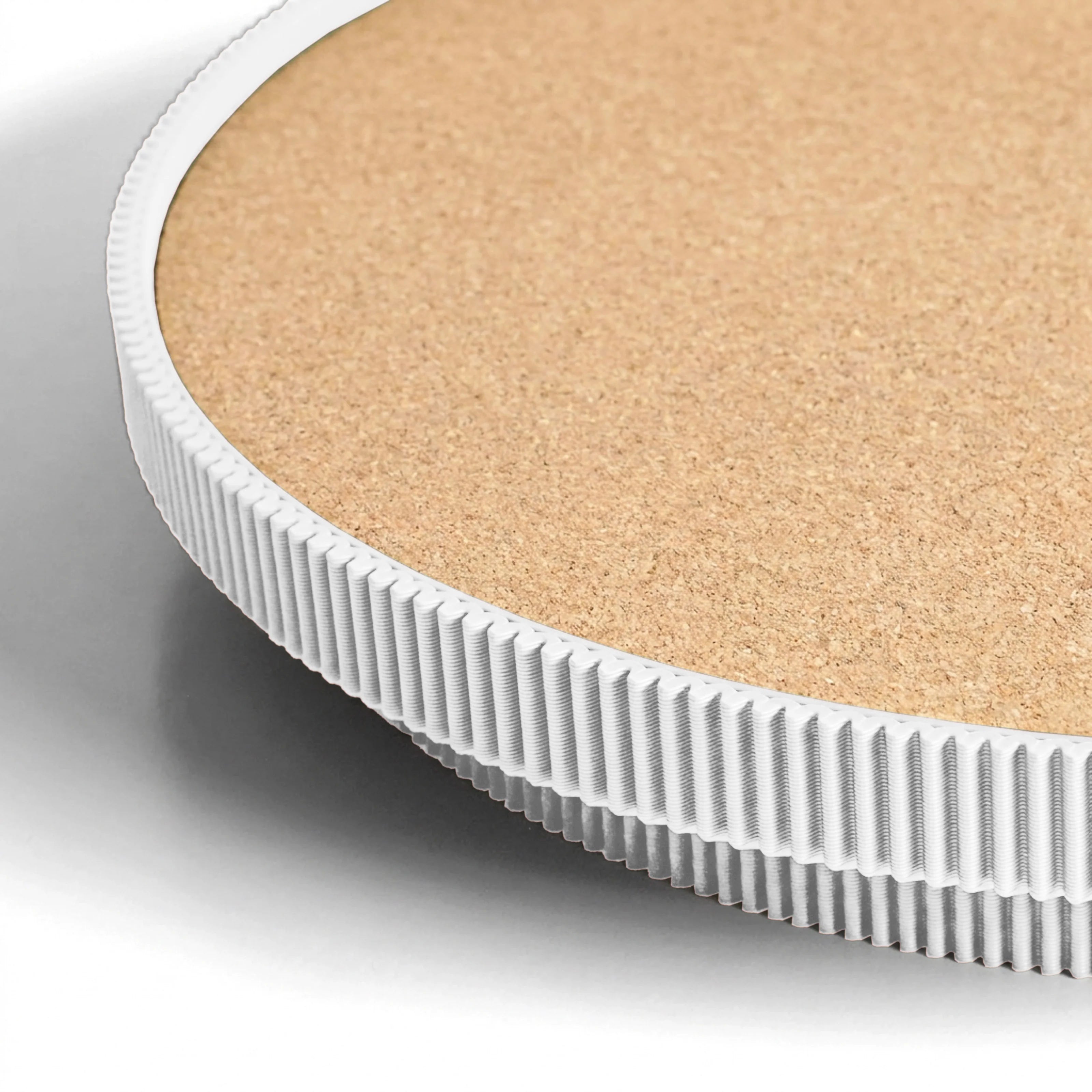 Close-up of a white circular serving tray with a cork top on a light gray background