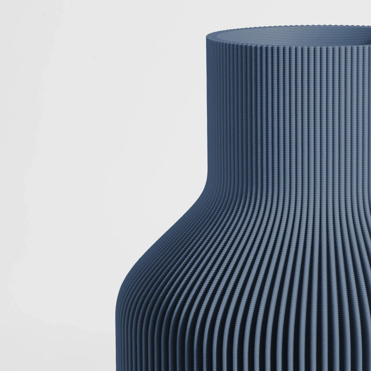 Close-up of a textured dark blue vase on a light gray background
