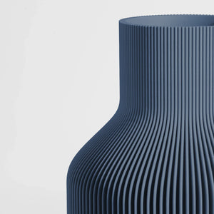 Close-up of a textured dark blue vase on a light gray background