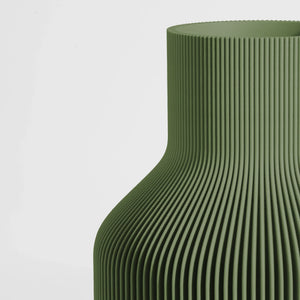 Close-up of a textured dark green vase on a light gray background