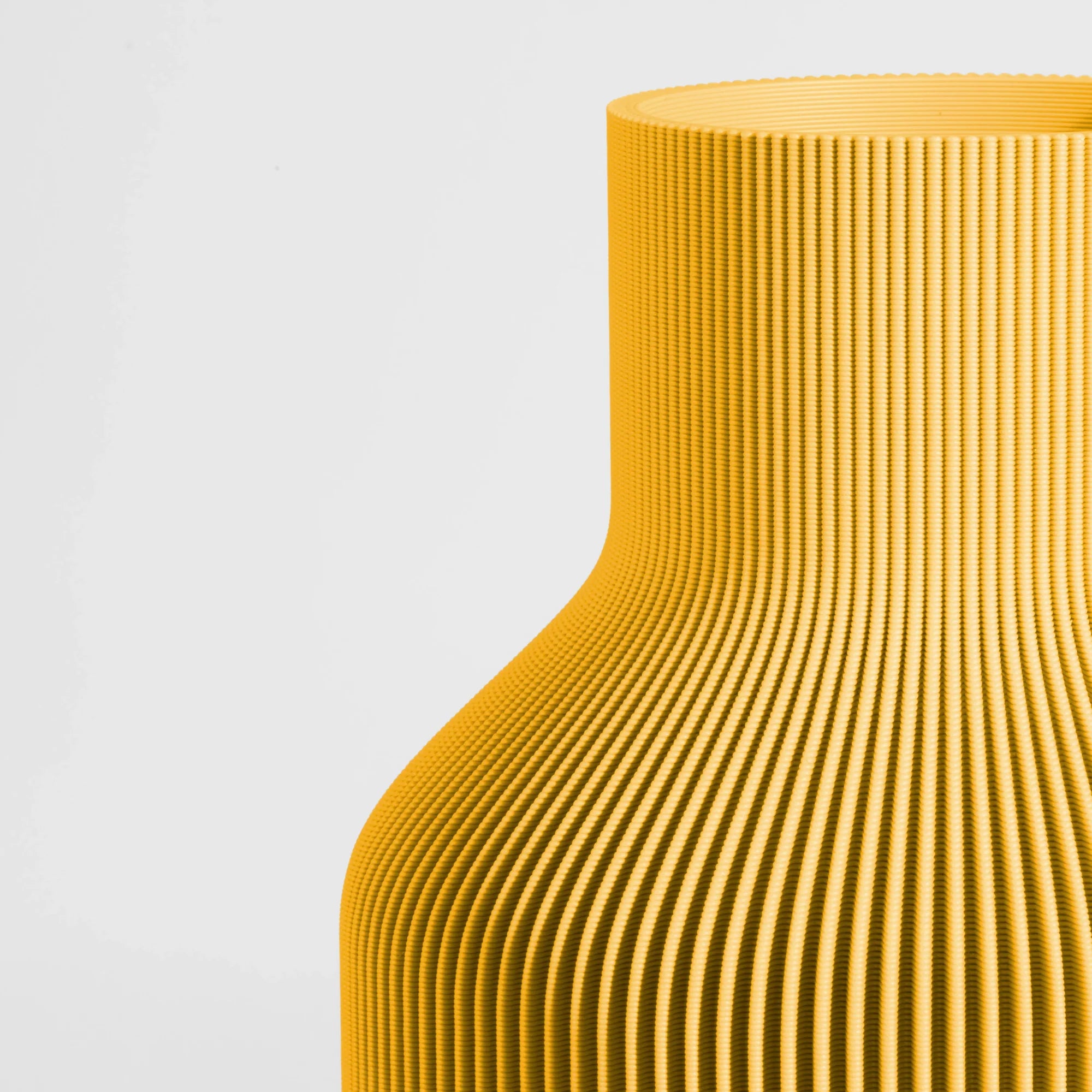 Close-up of a textured yellow vase on a light gray background.