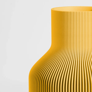 Close-up of a textured yellow vase on a light gray background.