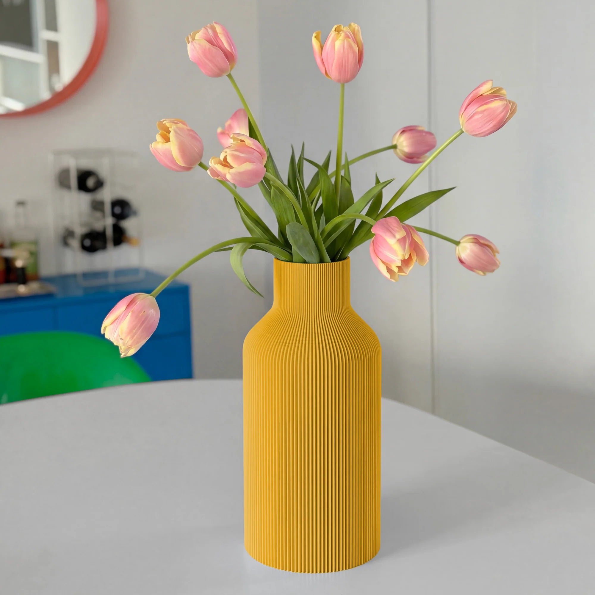 Mustard yellow ribbed vase with pink tulips on a white table