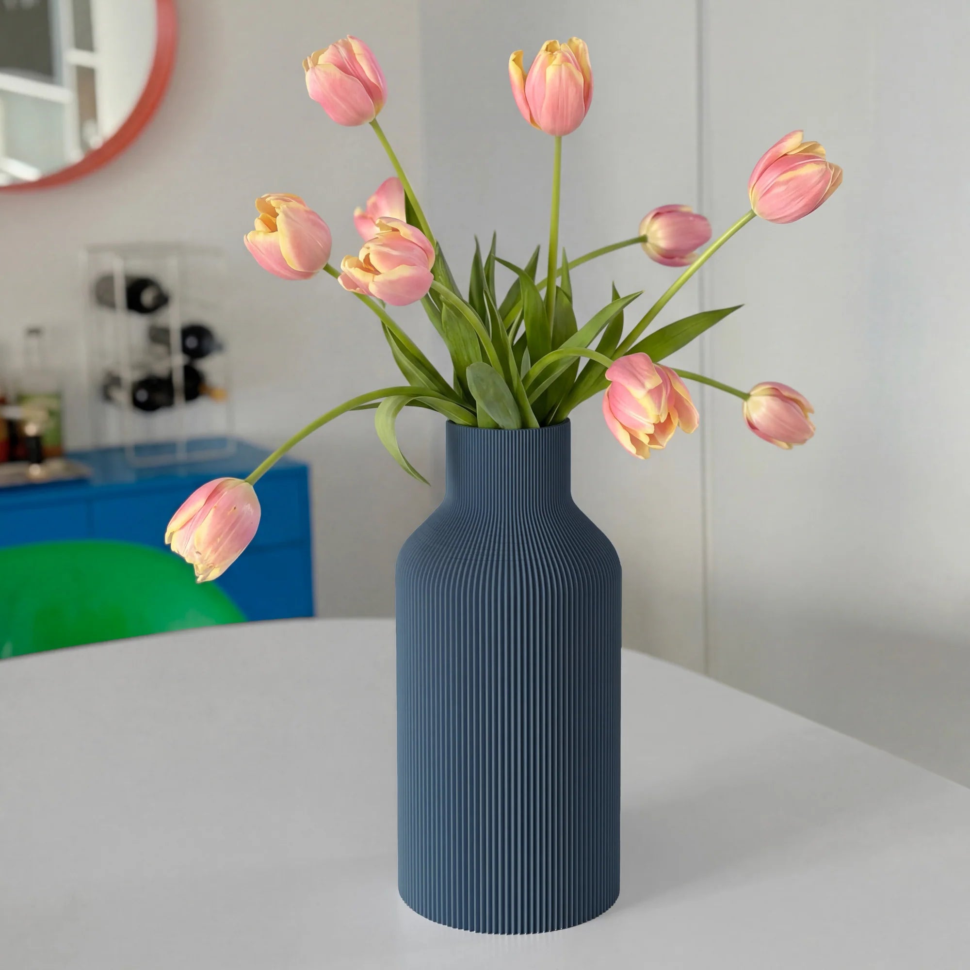 Navy blue ribbed vase with pink tulips on a white table