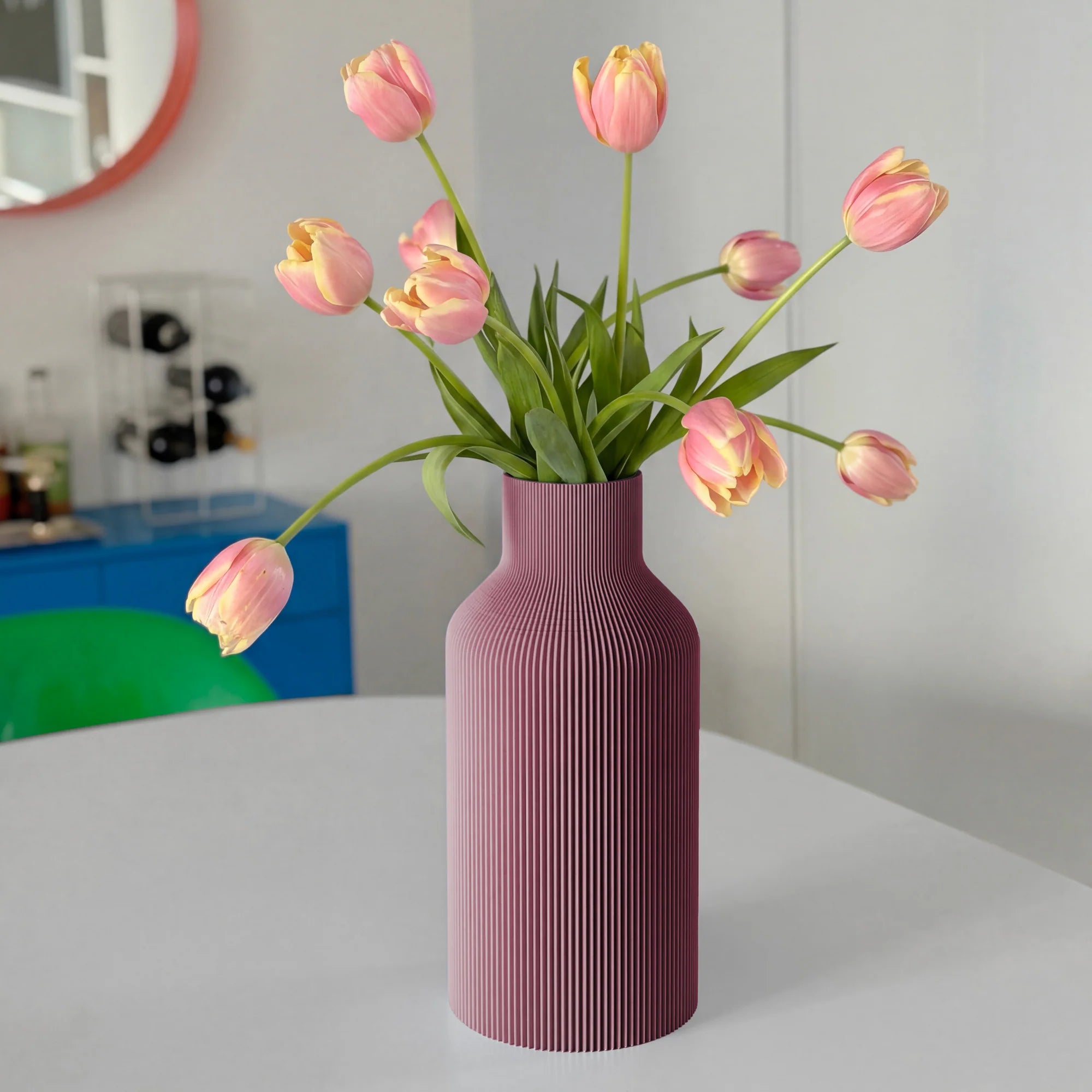 Purple ribbed vase with pink tulips on a white table.
