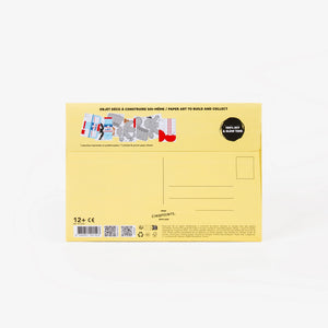 The back of a light yellow cardboard mailer envelope, featuring product details, address lines, stamp location, and a small graphic illustration, set against a clean white background.