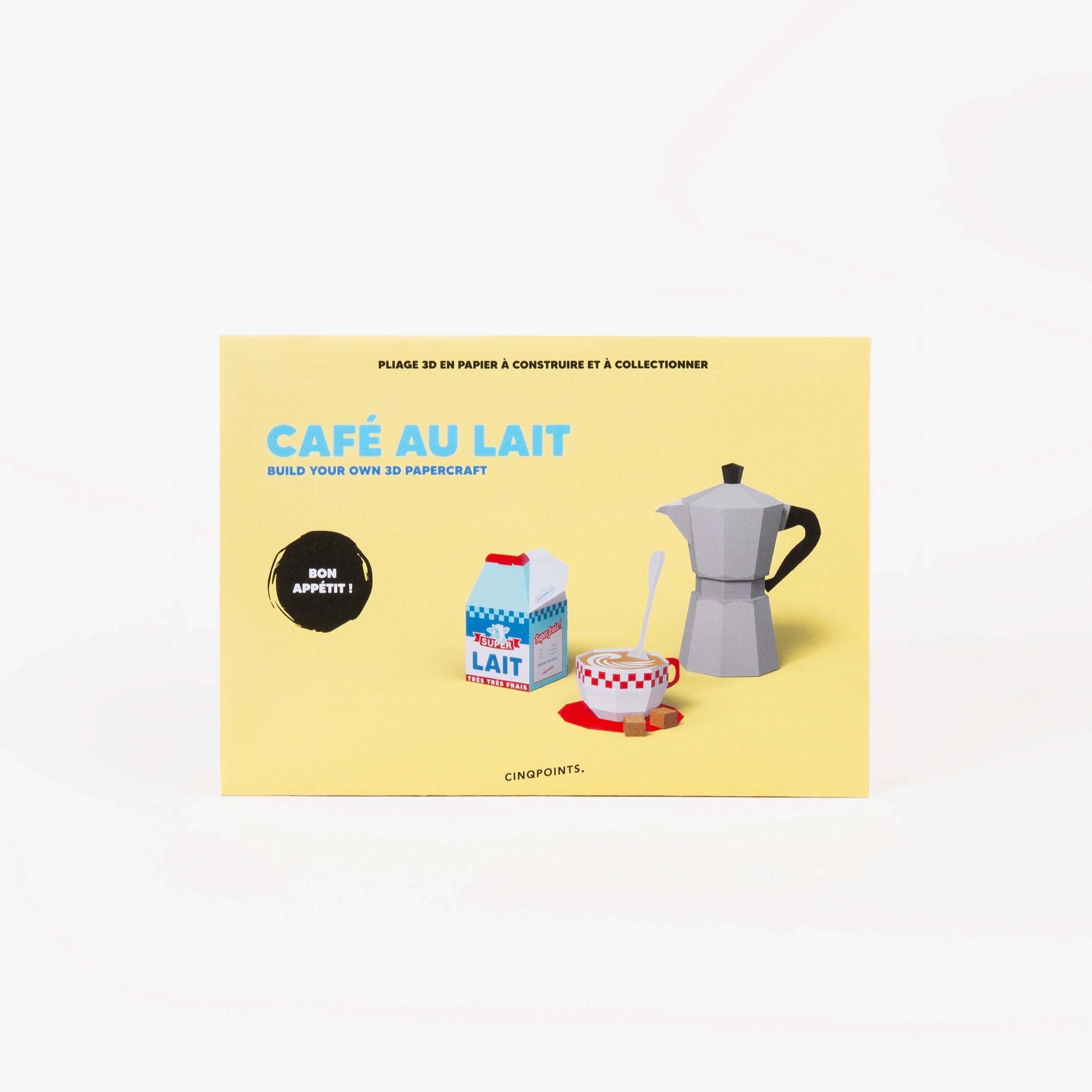A light yellow cardboard envelope for a cafe scene paper model set, featuring illustrations of a gray moka pot, a milk carton, and a red-and-white checkered coffee cup, photographed on a clean white background.