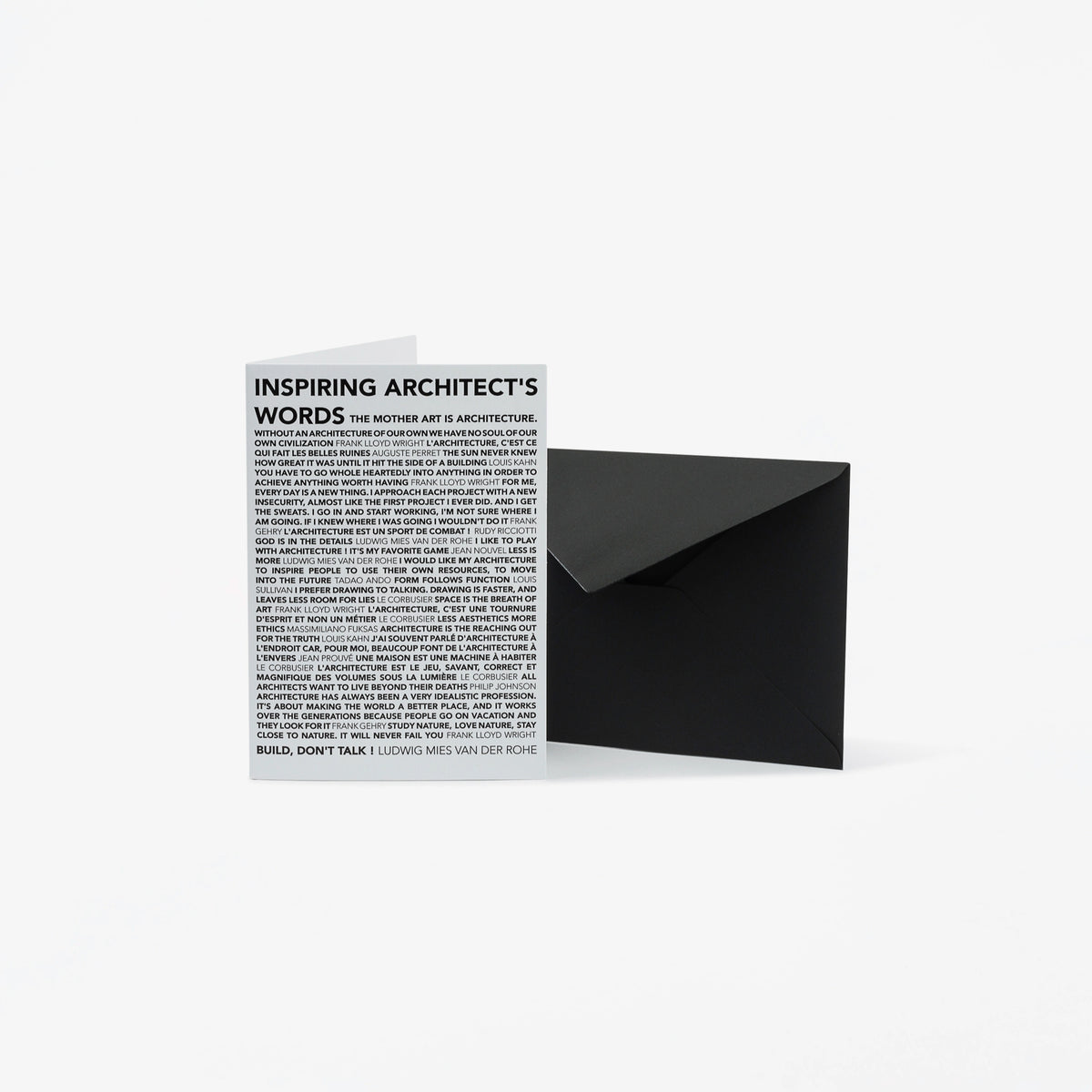 A minimalist black envelope standing next to a white greeting card printed with the text 'INSPIRING ARCHITECT'S WORDS' and dense small text below, on a clean white background.