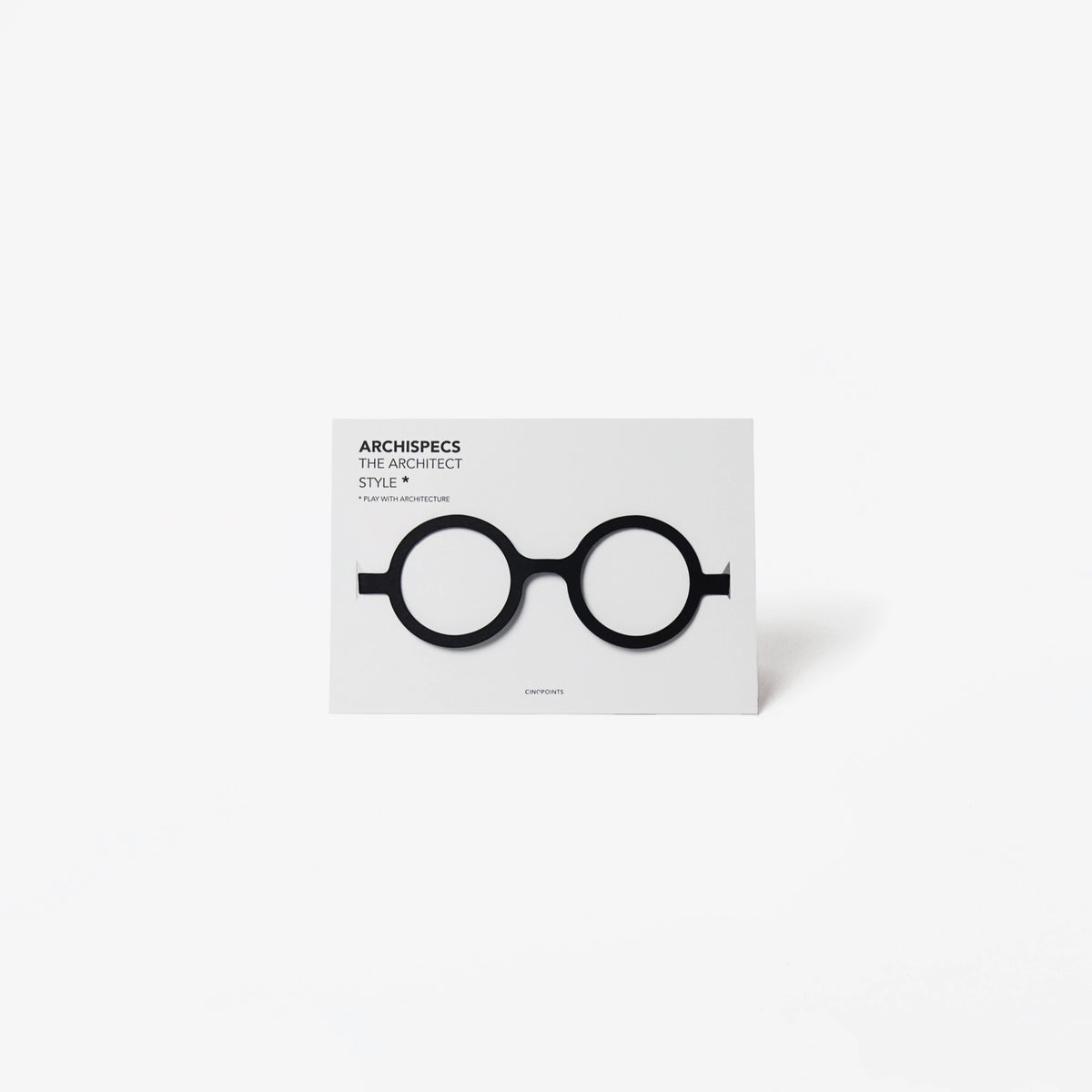 A minimalist architectural card featuring a white card with black cut out cardboard circular eyeglass, shown on a light gray background.