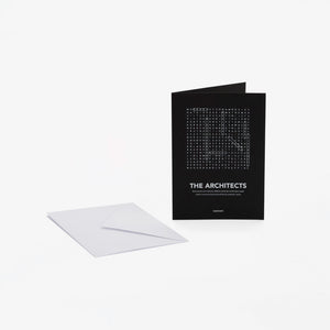 A black greeting card with white text "The Architects" and a word-search style crossword, shown standing upright next to a white envelope on a light gray background.