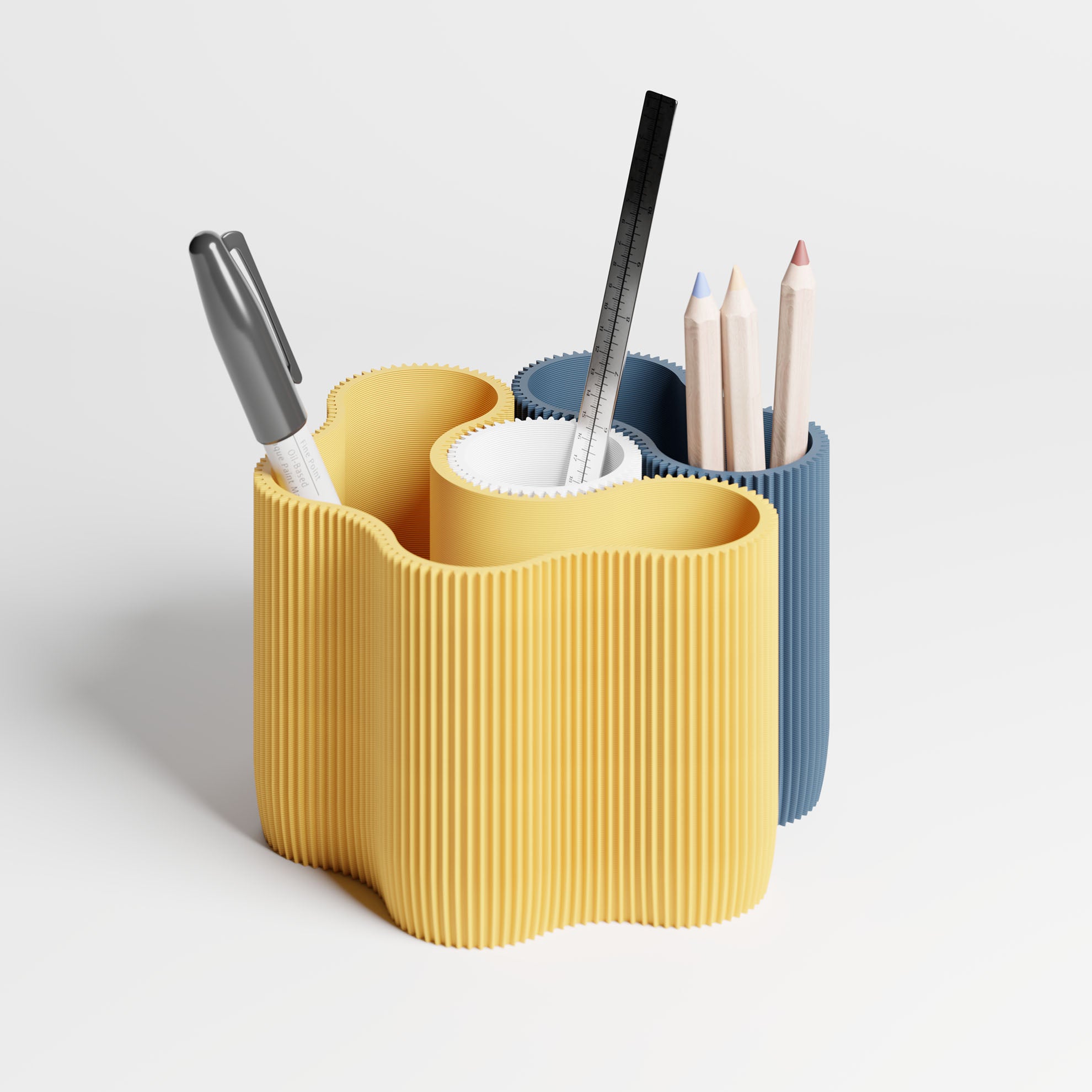 A modern three-compartment desk organizer with a wavy, ribbed design. The front compartment is mustard yellow, the middle is white, and the back compartment is blue.