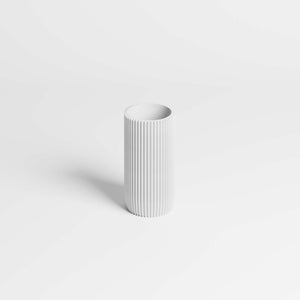 A minimalist white pen holder with vertical fluted ridges, standing on a clean white background with a soft shadow.