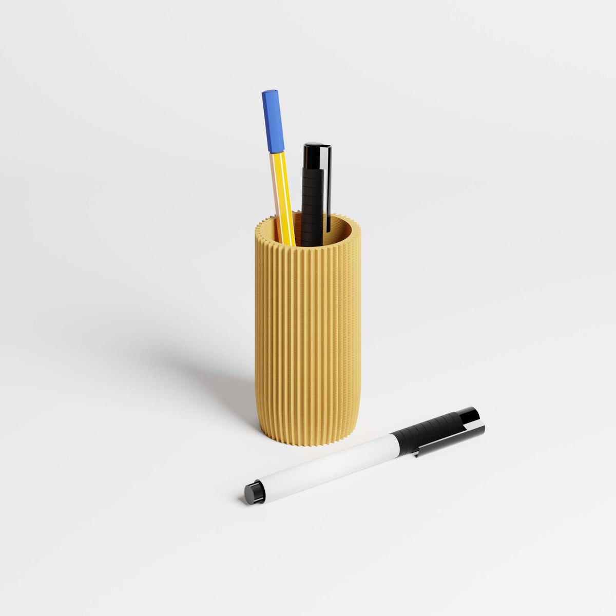 Textured yellow pen holder with three pens on a light gray background