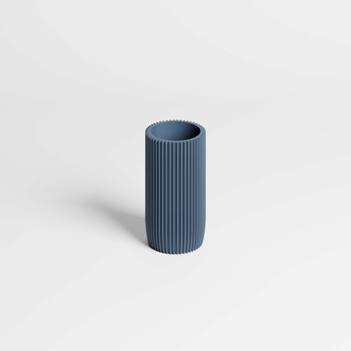 A modern, ribbed cylindrical vase in a muted slate blue color, standing upright on a clean white background.