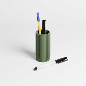 Olive green ribbed pen holder with pens on a light gray background