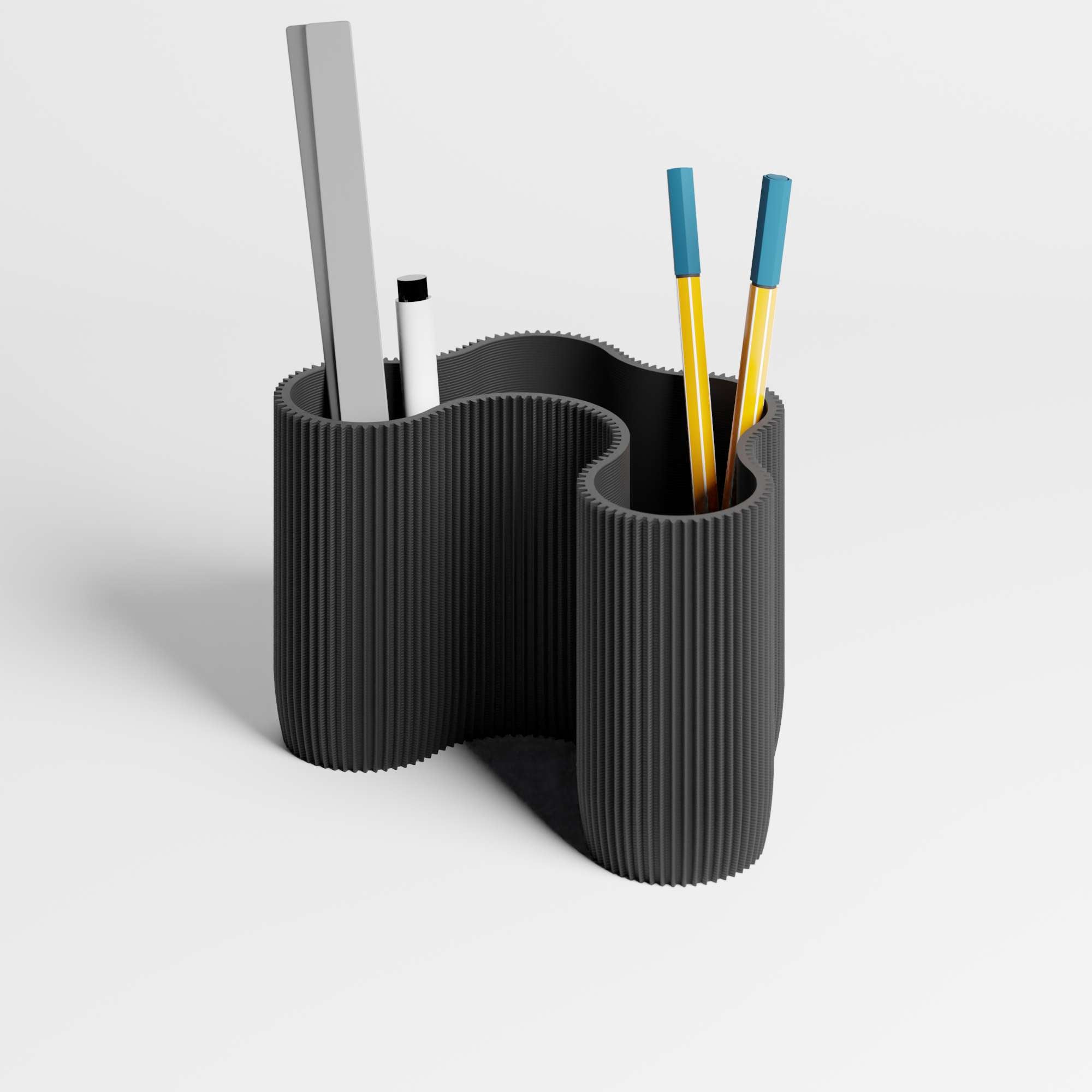 A flowing ribbed desk organiser in a black colour with pens and a ruler inside it, shown on a clean light gray studio background.