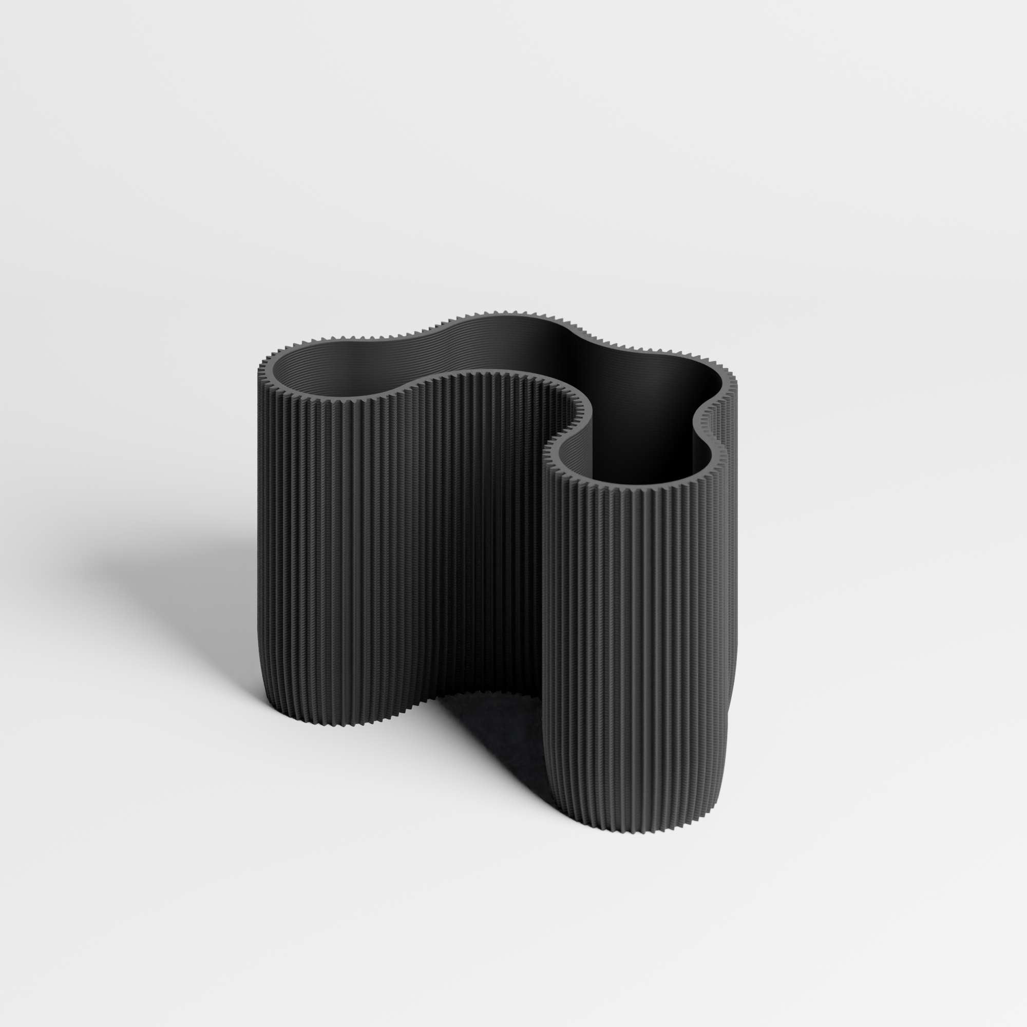A flowing ribbed desk organiser in a black colour, shown on a clean light gray studio background.