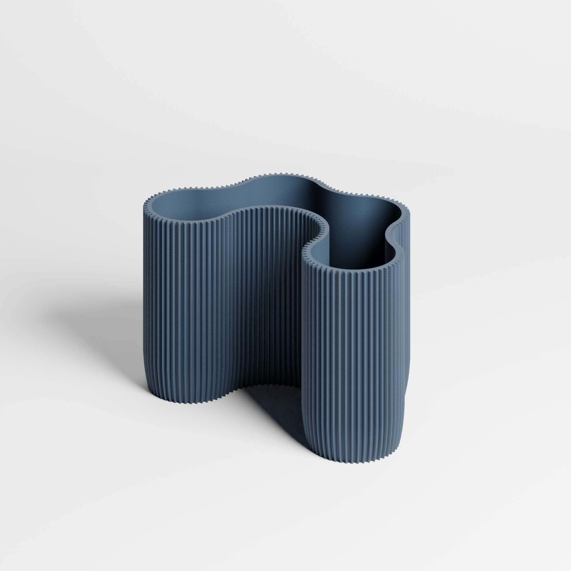 A modern, sculptural ribbed desk organiser in a muted navy blue colour, shown on a clean light gray studio background.