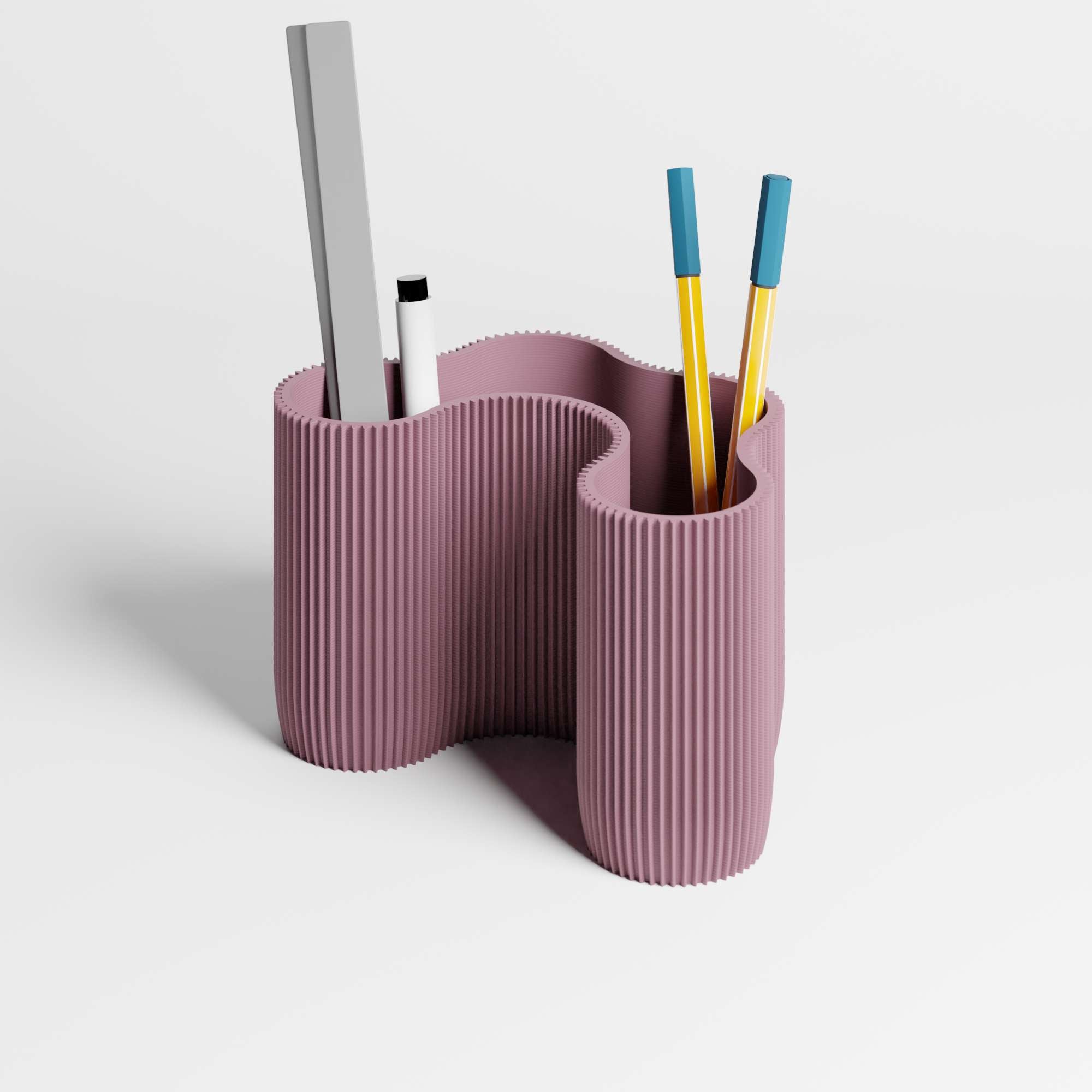A four-compartment dusky-purple desk organiser with a wavy, ribbed design, on a white background with pens and a ruler inside it.