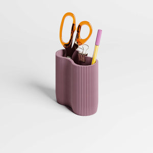 Purple ribbed pen holder with scissors, clips, and a pen on a light gray background.