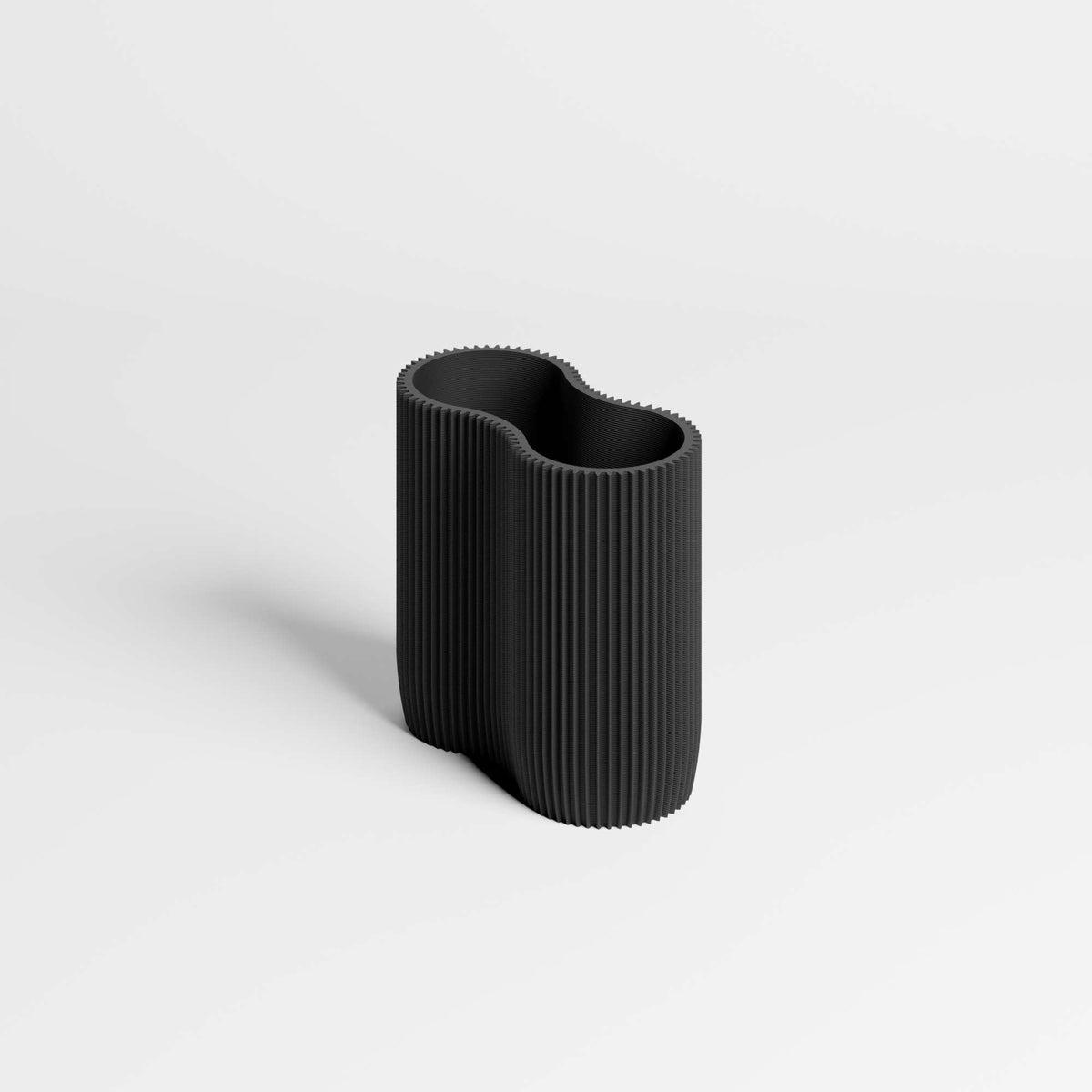 A modern, black ribbed pen holder with an organic, wavy silhouette, shown on a clean light gray background.