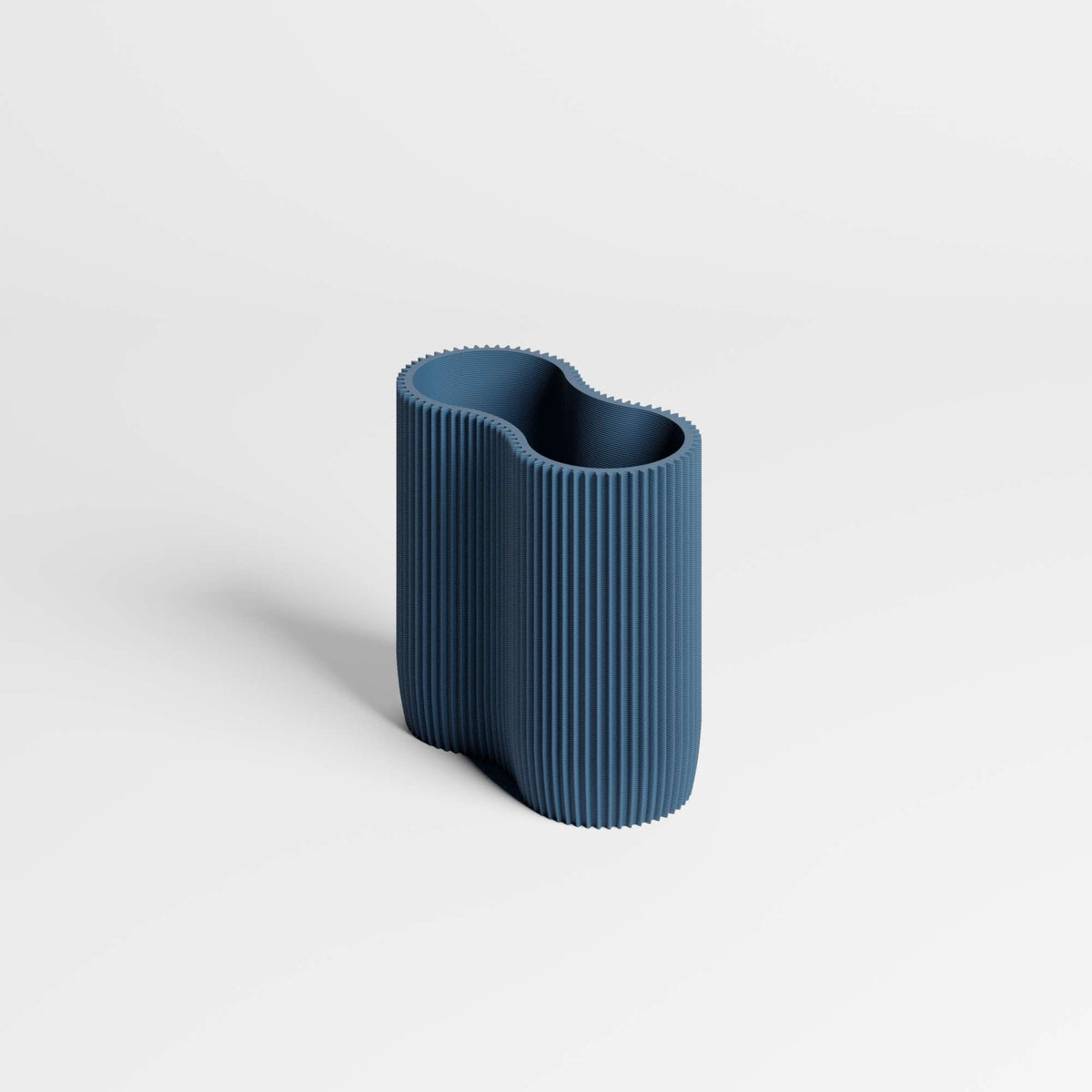 A modern, wavy pen holder in a textured navy blue colour with vertical fluting, set against a clean white background.