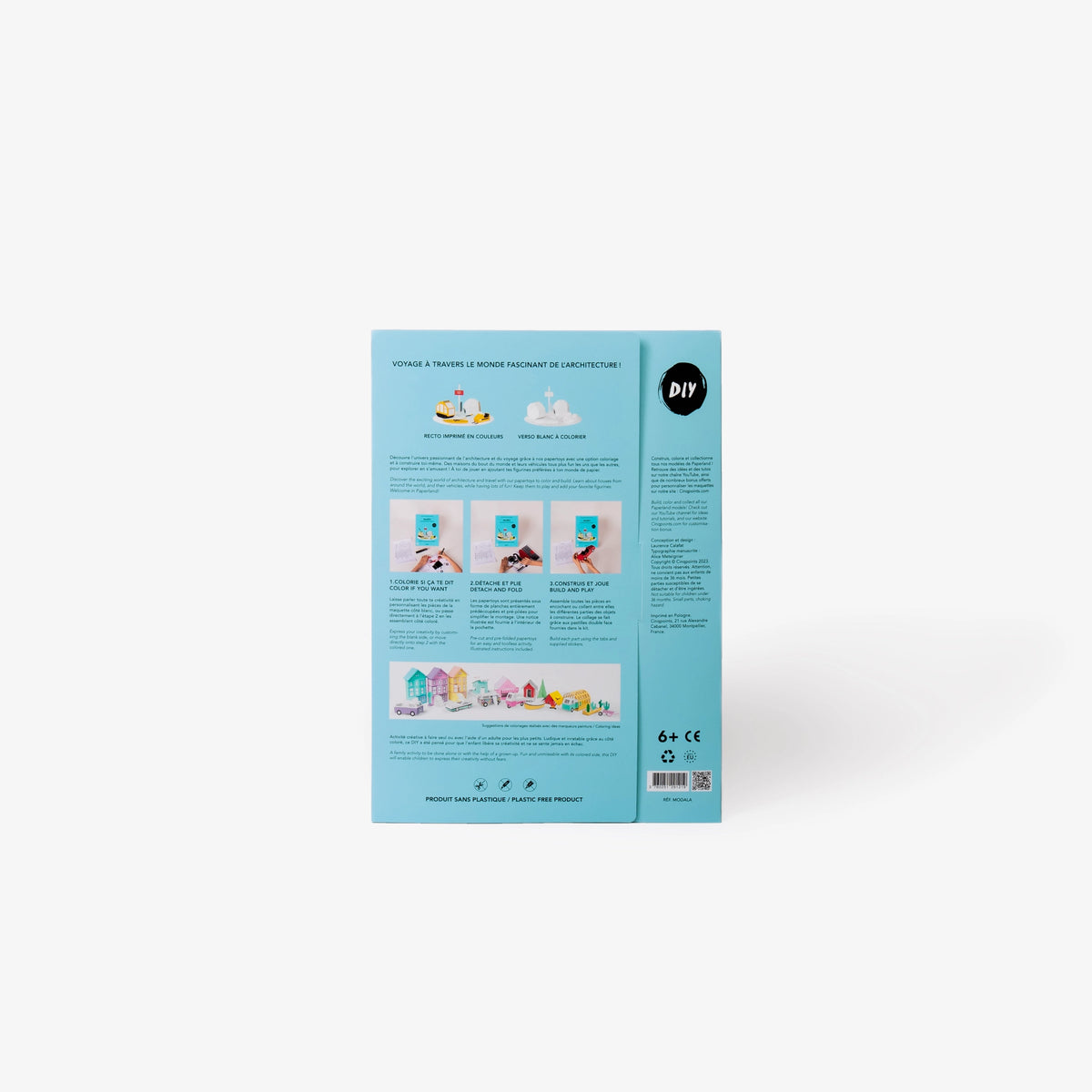 The back cover of a light blue cardboard folder of a paper model kit stands upright on a clean white background, showing instructional text, and three small photos of hands working with white paper.