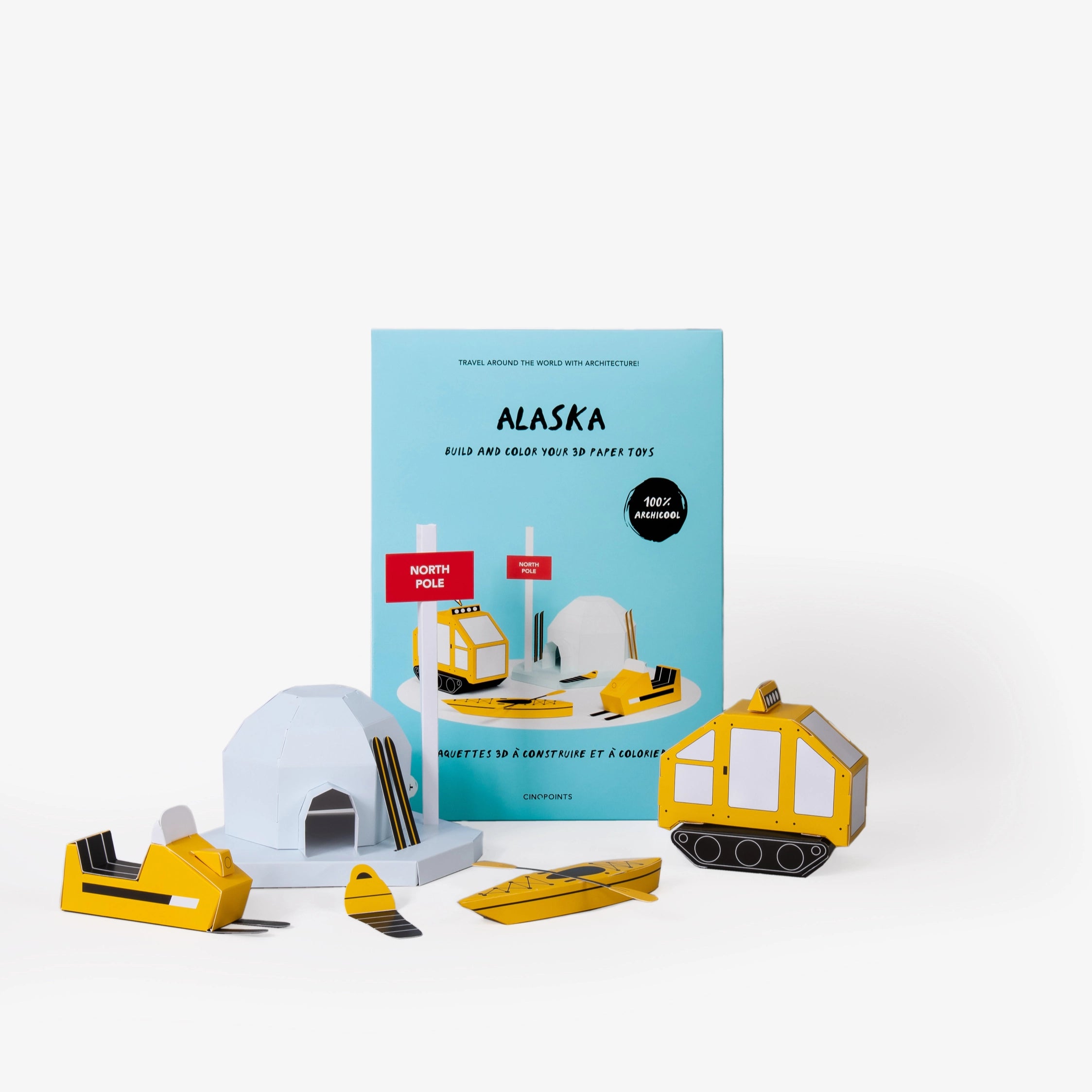 Alaska paper model kit folder featuring a light blue cover standing upright behind  several assembled and coloured in paper craft models including a north pole sign, igloo, snowmobile and other winter items against a clean white background.

