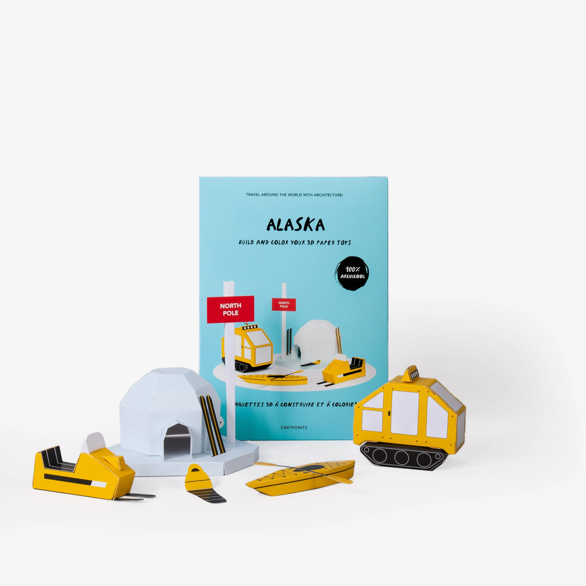 Alaska paper model kit folder featuring a light blue cover standing upright behind  several assembled and coloured in paper craft models including a north pole sign, igloo, snowmobile and other winter items against a clean white background.

