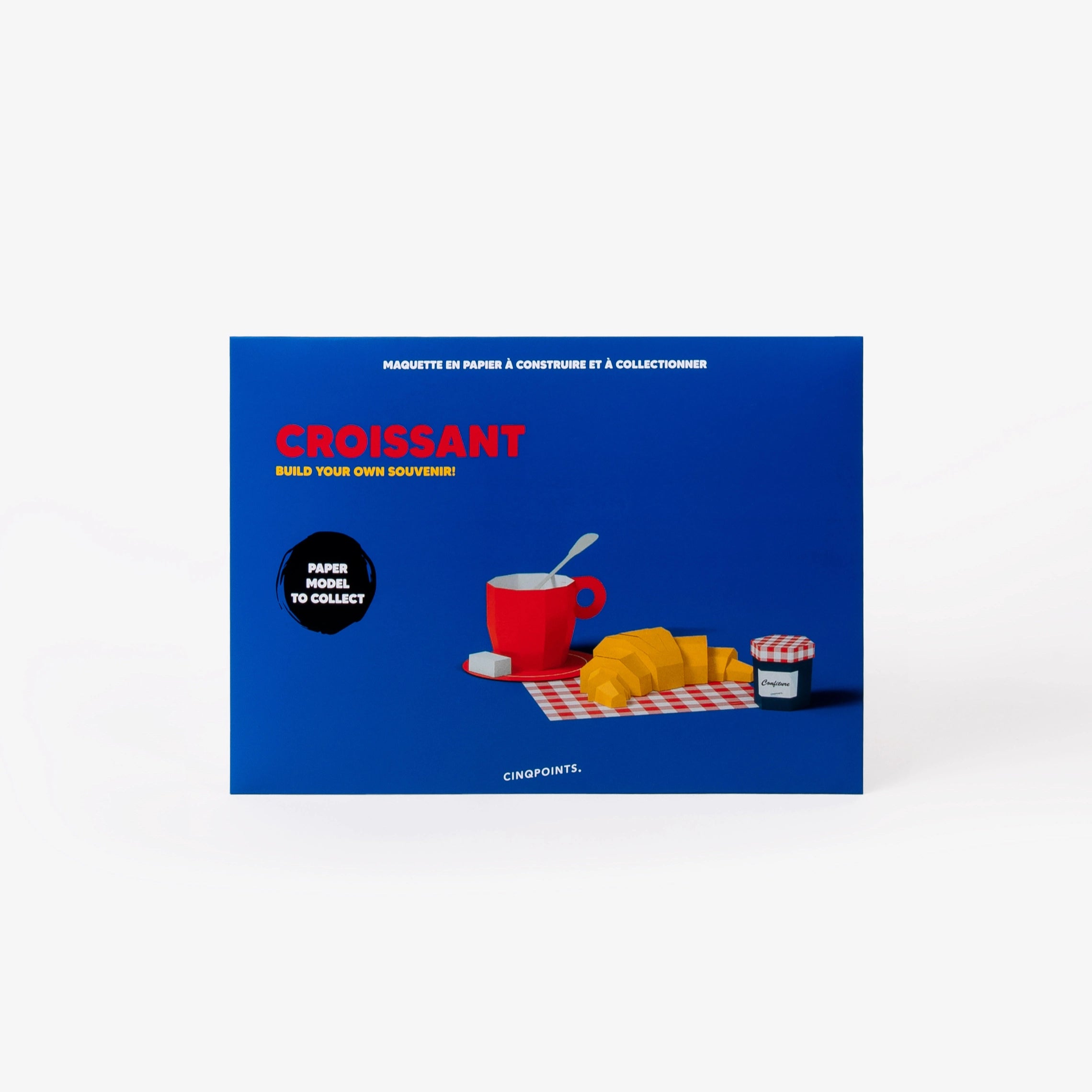 A blue collectible paper model kit envelope, featuring an illustration of a red mug, croissant, and a jam jar on a white background.