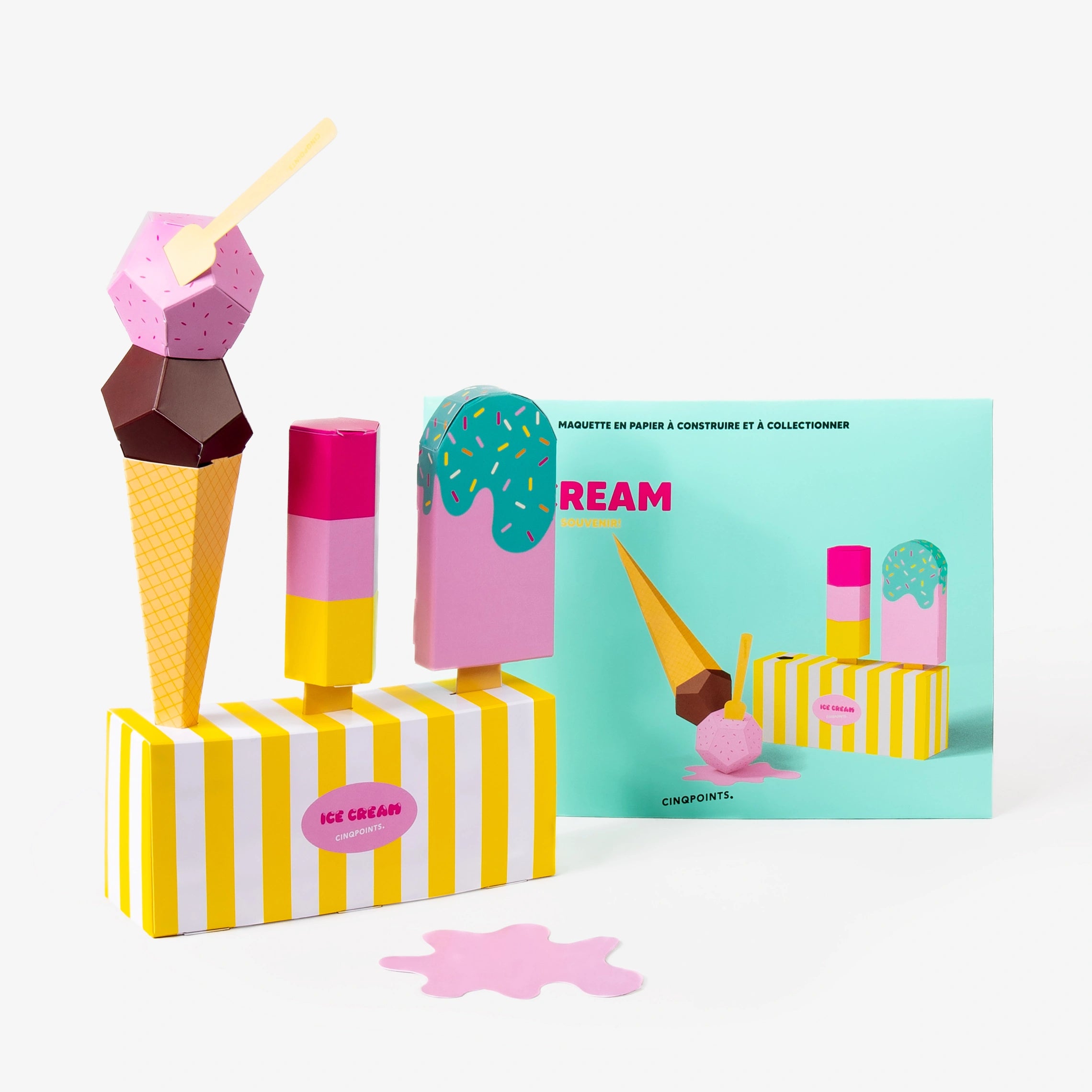 A turquoise cardboard envelope for ice cream paper models set behind, and in front a colourful paper set of an ice cream cone, 2 different ice creams, and a striped dessert box, photographed on a clean white background.