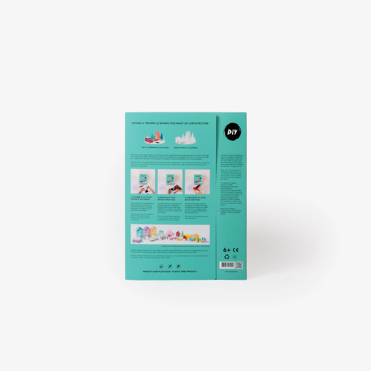 The back cover of a teal cardboard folder of a paper model kit stands upright on a clean white background, showing instructional text, and three small photos of hands working with white paper.