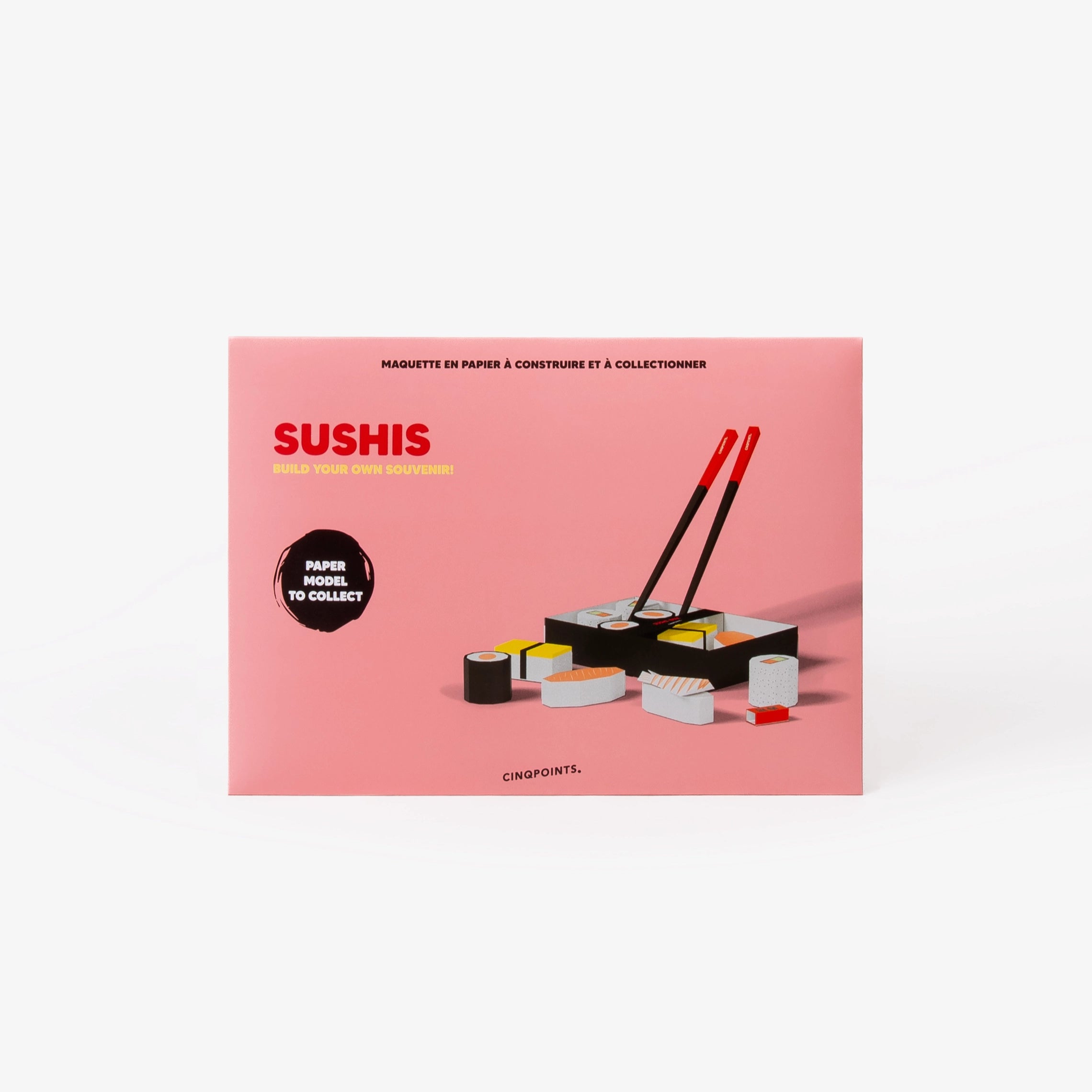 A pink cardboard envelope for a sushi paper model collector set, featuring illustrations of sushi pieces and a black-and-red chopsticks set, photographed on a clean white background.