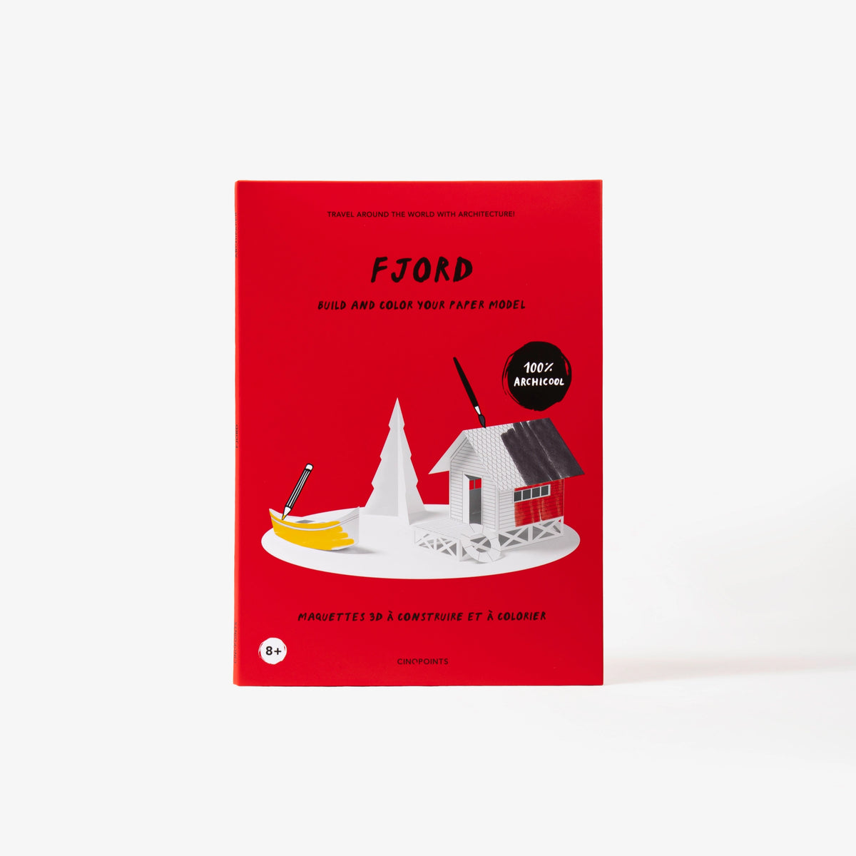 A red cardboard folder of a paper model kit stands upright against a clean white background. The cover shows a stylised illustration of a white hut, tree and a small yellow boat and paintbrushes and pencil.
