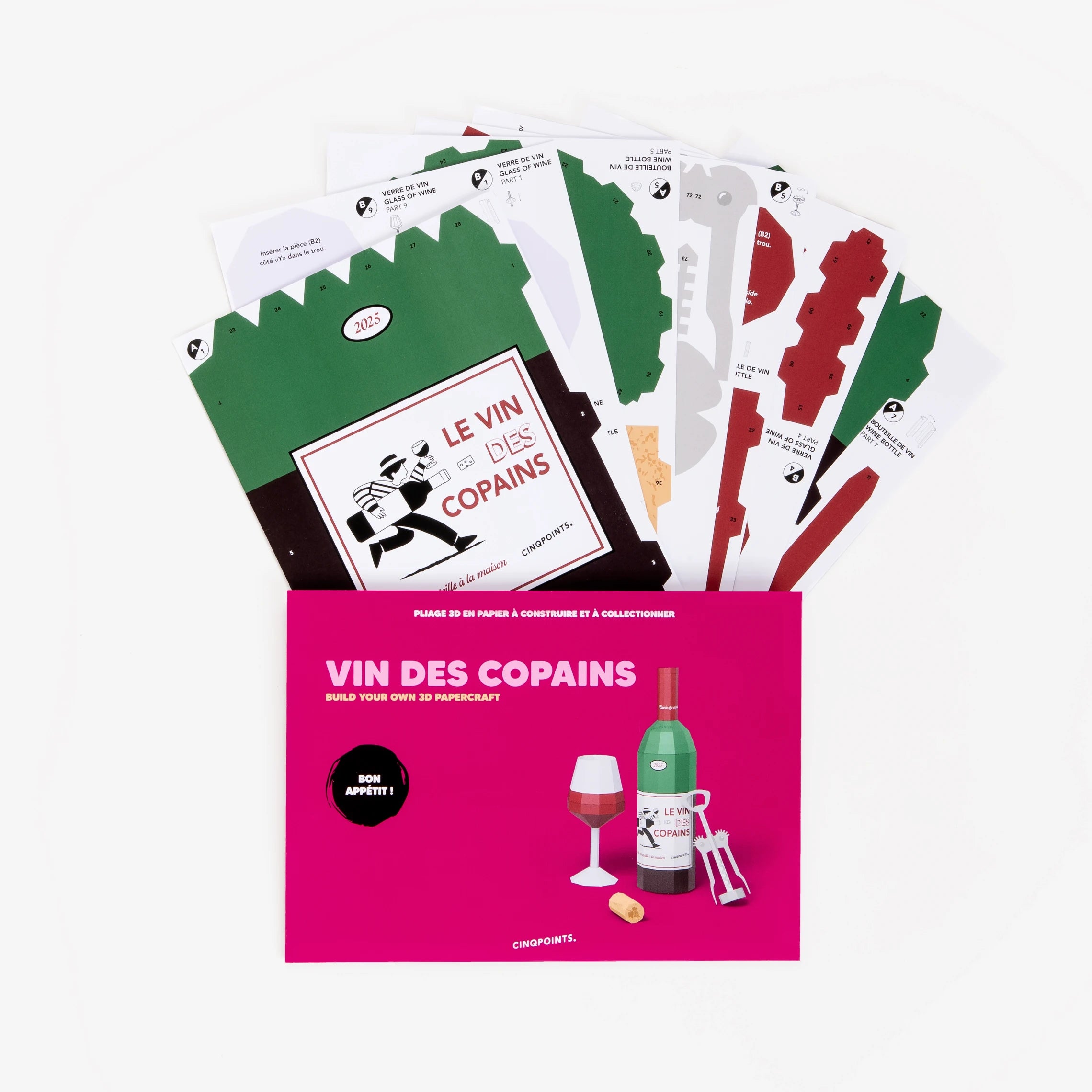 A DIY paper wine scene craft kit, shown with its pink packaging envelope and several fanned-out printed card templates on a clean white background.