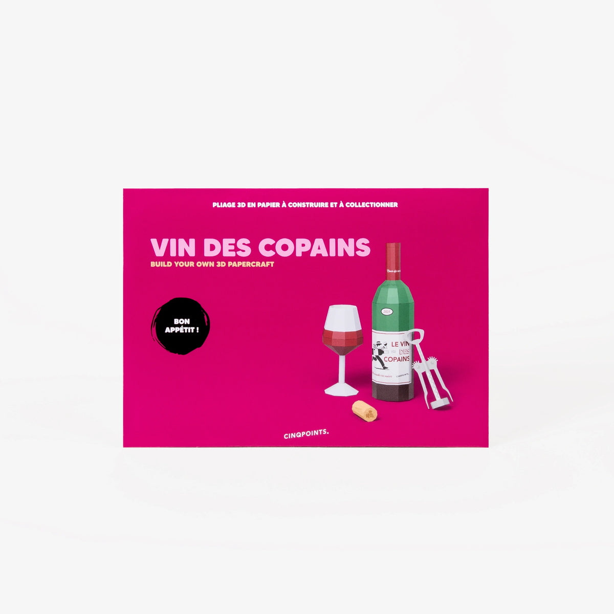 A pink cardboard envelope for a wine paper model scene set, featuring illustrations of a wine bottle, wine glass, corkscrew, and cork on the front, photographed on a clean white background.